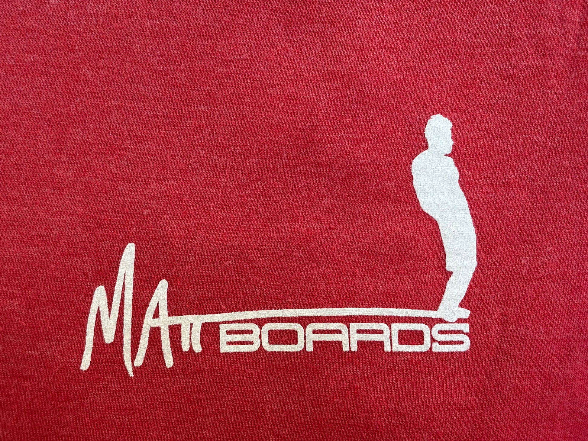 Red shirt color with white 'Matt Boards' logo featuring a silhouette of a person on a surfboard.