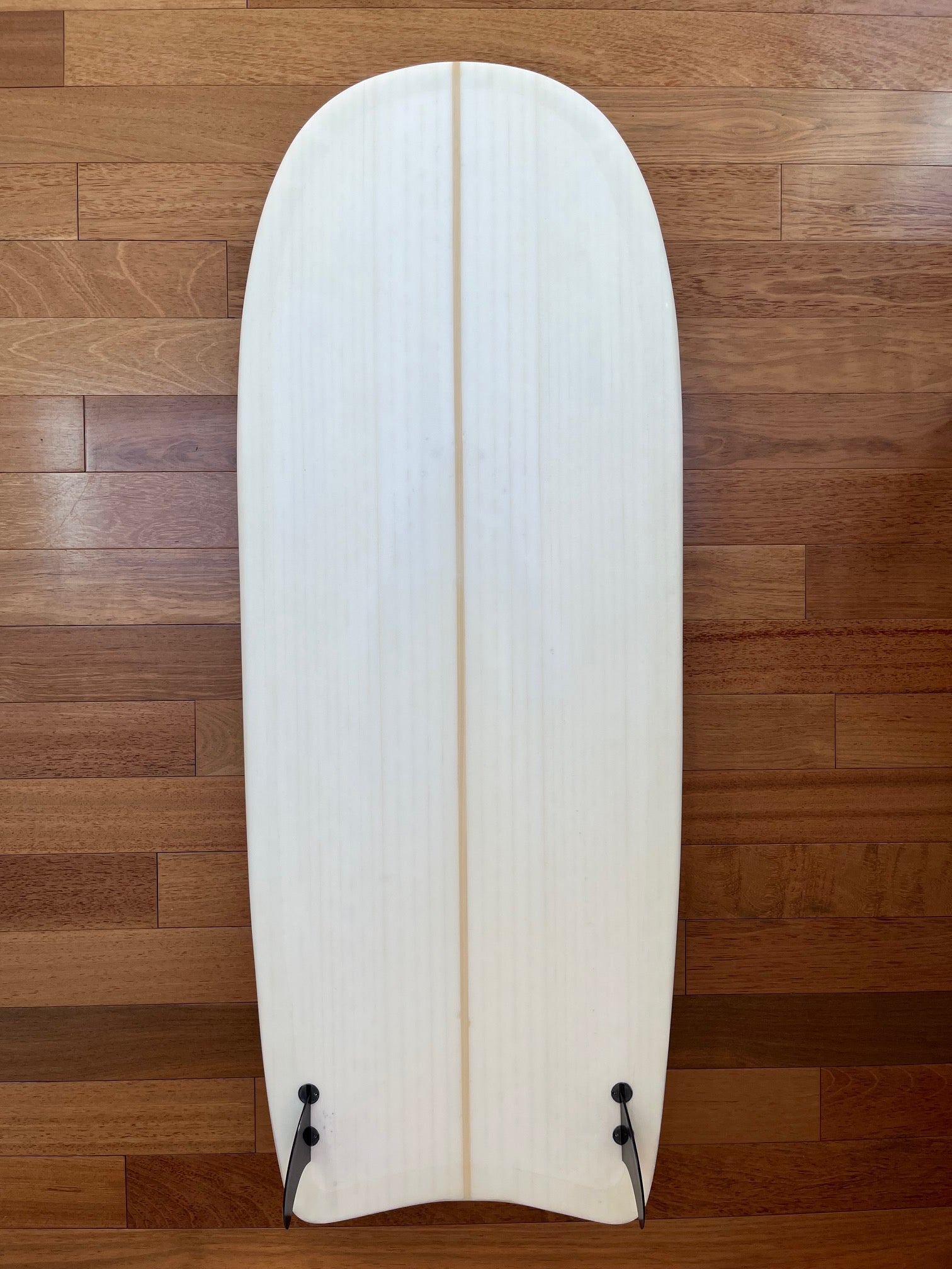 White surfboard bottom view showing fins