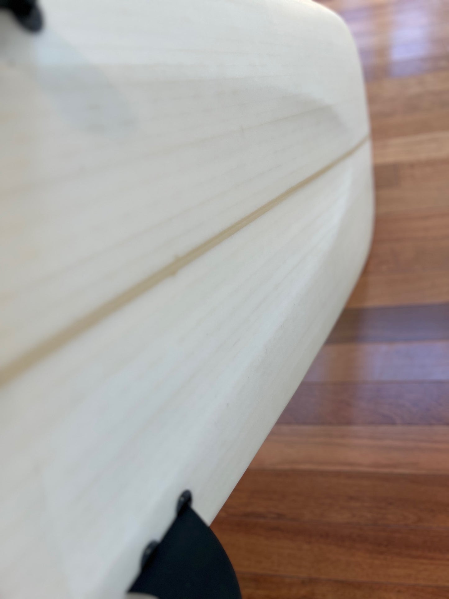 Bottom view of white surfboard showing concave in bottom and fins