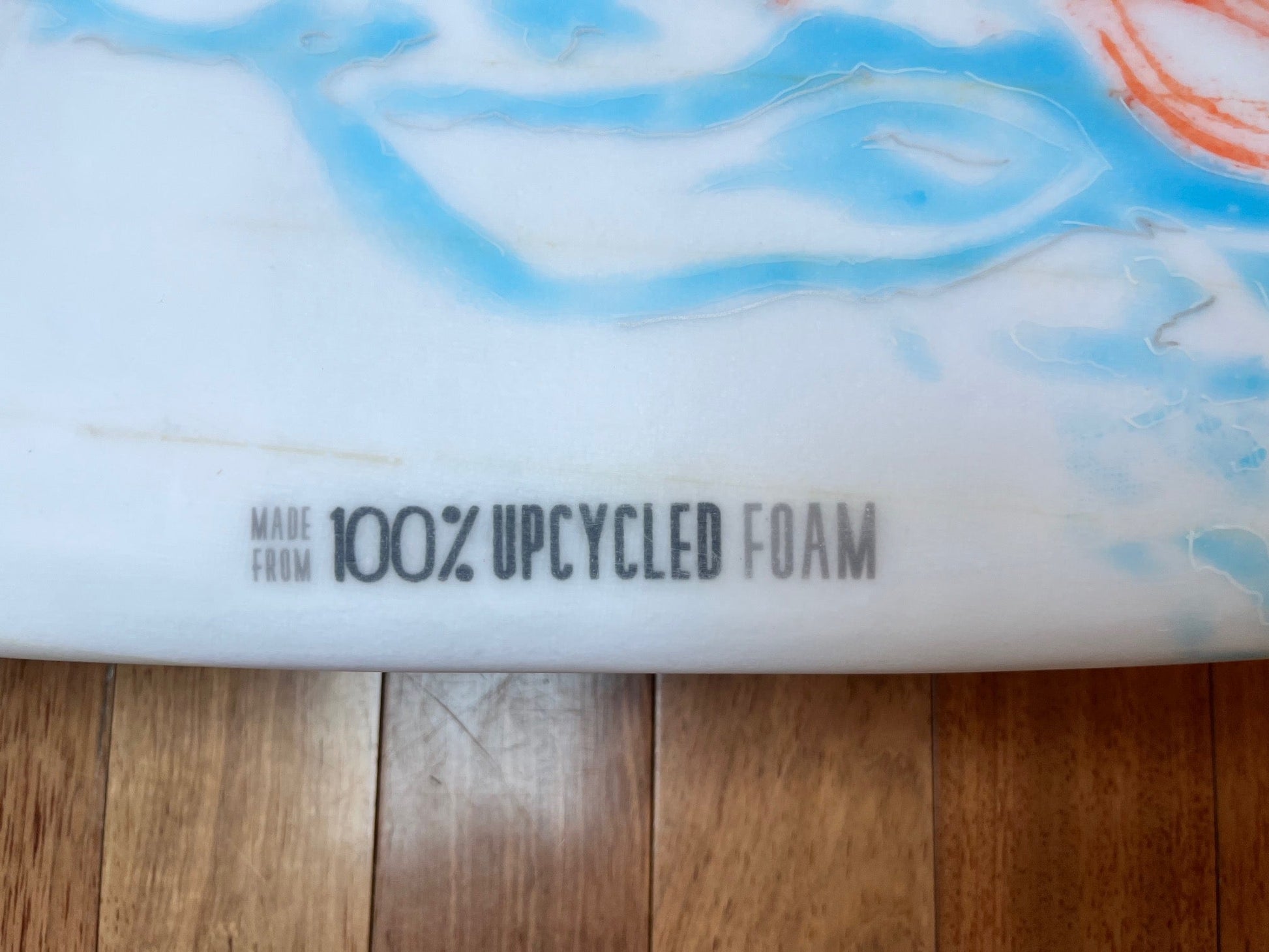 Label on side of board that says 'Made from 100% Upcycled Foam' over a wooden background.