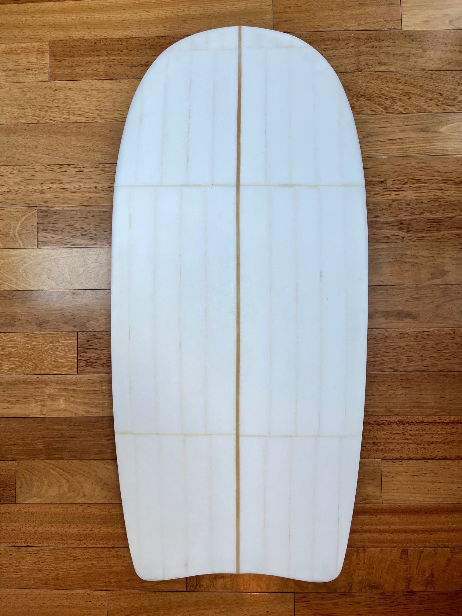 White body board with visible foam lines on a wooden background