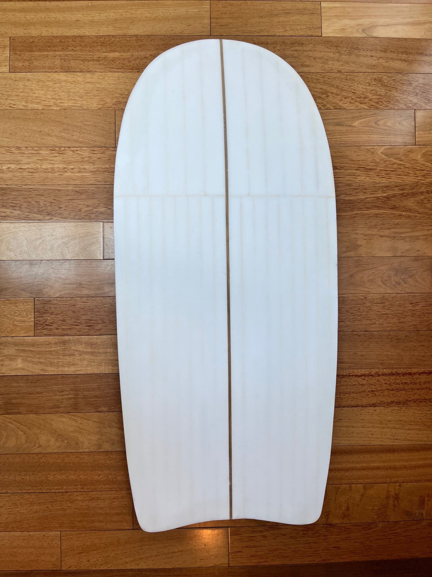 White body board with visible foam lines on a wooden background