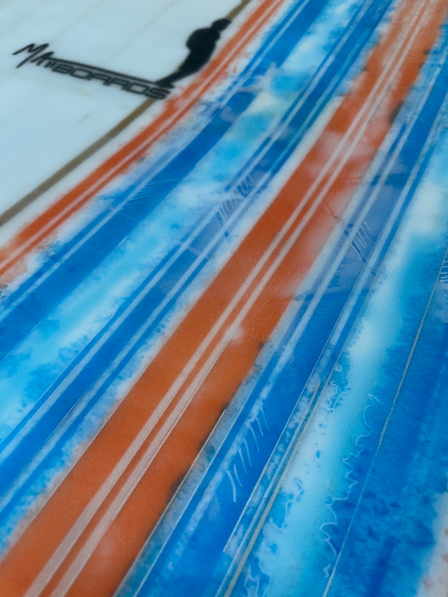 Close-up detail of blue and orange stripes with splattered color and line art with a Matt Boards logo in the background