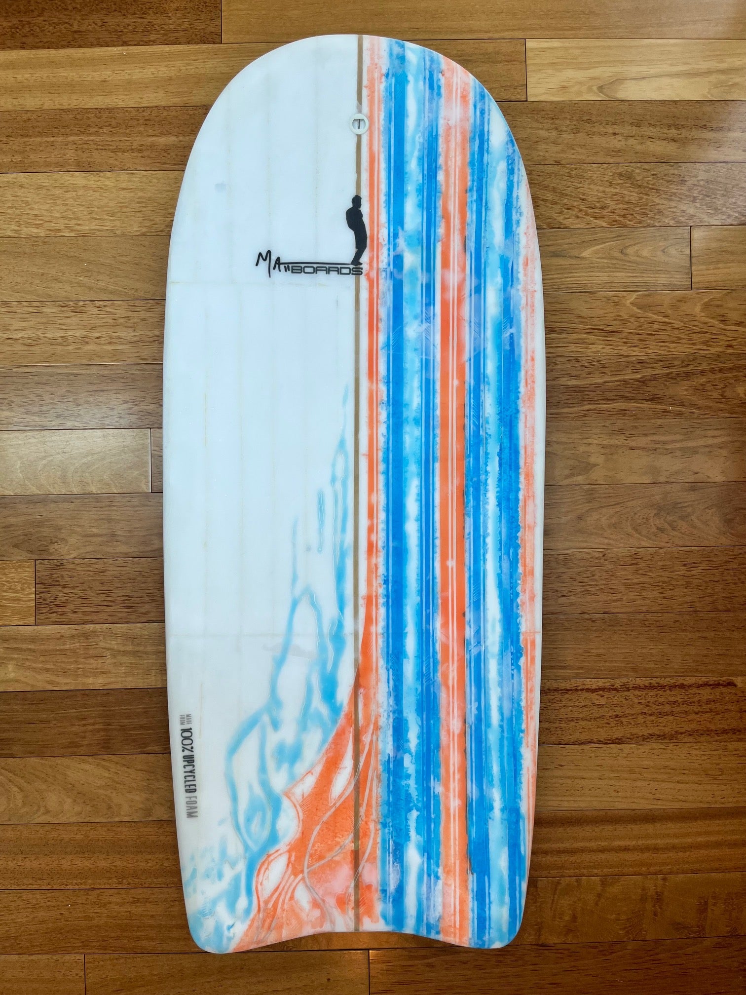 Colorful bodyboard with blue and orange stripes and splattered color with a Matt Boards logo on a wooden background