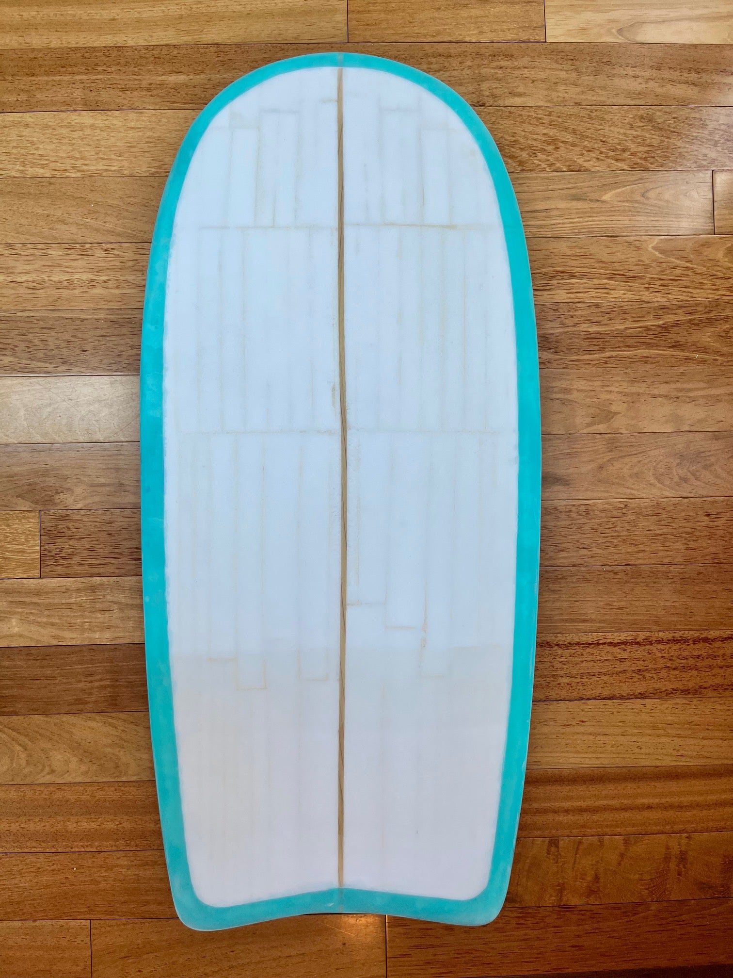 White bodyboard with turquoise edge on a wooden background