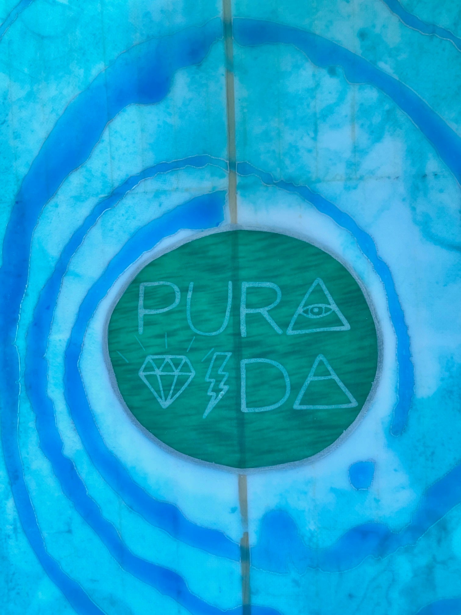 Bodyboard with 'Pura Vida' design in a green circle on a turquoise and blue swirl background